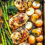Raw chicken and vegetables arranged on sheet pan before roasting with garlic butter