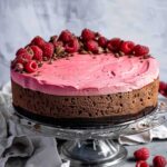 Whole vegan chocolate raspberry mousse cake decorated with fresh raspberries