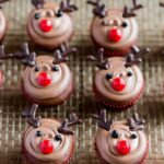 Easy reindeer cupcakes with chocolate antlers and red noses arranged on festive holiday platter