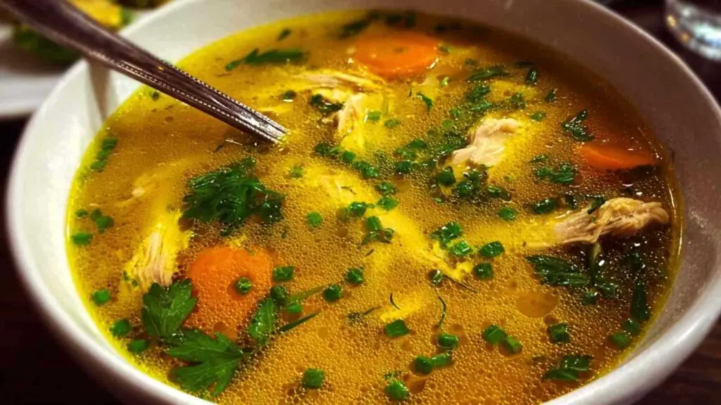 Anti-inflammatory turmeric chicken soup in white bowl garnished with cilantro