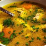 Anti-inflammatory turmeric chicken soup in white bowl garnished with cilantro