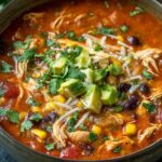 Bowl of chicken enchilada soup topped with cheese, sour cream, and cilantro