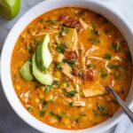 Creamy chicken tortilla soup in white bowl topped with tortilla strips and cheese