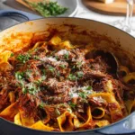 Dutch oven short rib ragu with pappardelle pasta topped with parmesan cheese