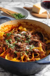 Dutch oven short rib ragu with pappardelle pasta topped with parmesan cheese