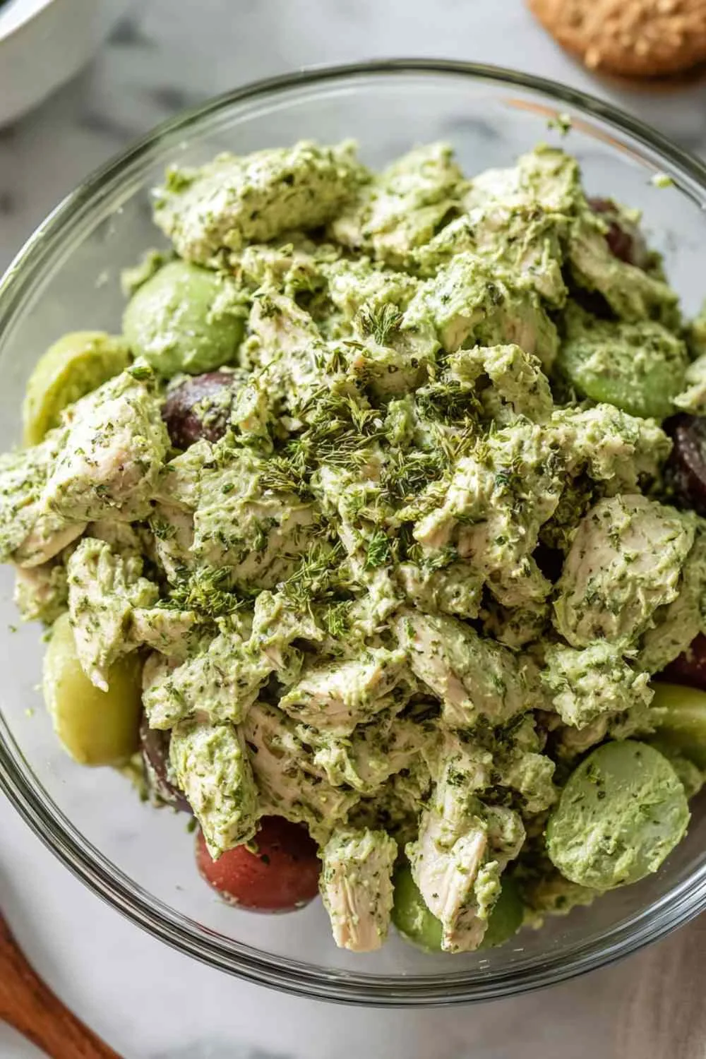 Green Goddess Chicken Salad in white bowl topped with fresh herbs