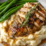 Garlic herb chicken with mashed potatoes and green beans on a white dinner plate with golden gravy