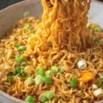 High protein vegan saucy ramen noodles in white bowl topped with tofu edamame and sesame seeds