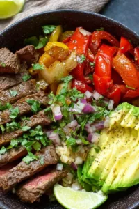 High protein steak fajita bowl with sliced skirt steak, cauliflower rice, and roasted bell peppers in white bowl