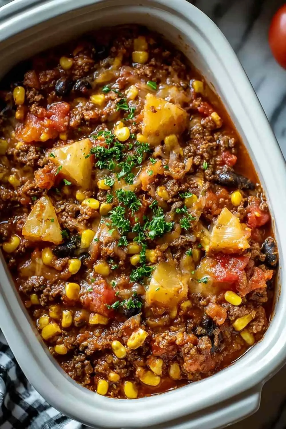 Slow Cooker Cowboy Casserole in white bowl topped with melted cheese and chives