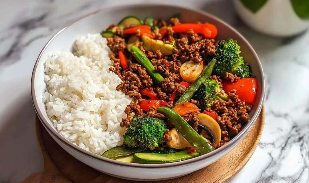 Spicy ground beef stir-fry bowl with colorful vegetables and steamed rice in white bowl