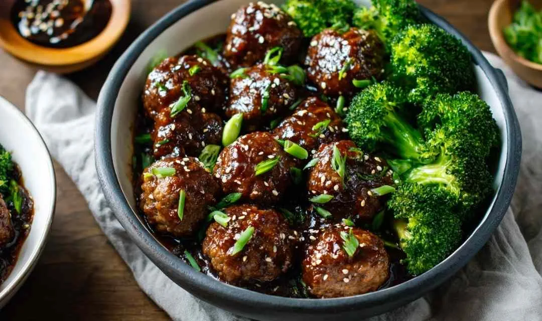 Sticky Mongolian meatballs and broccoli served over white rice with sesame seeds and green onions