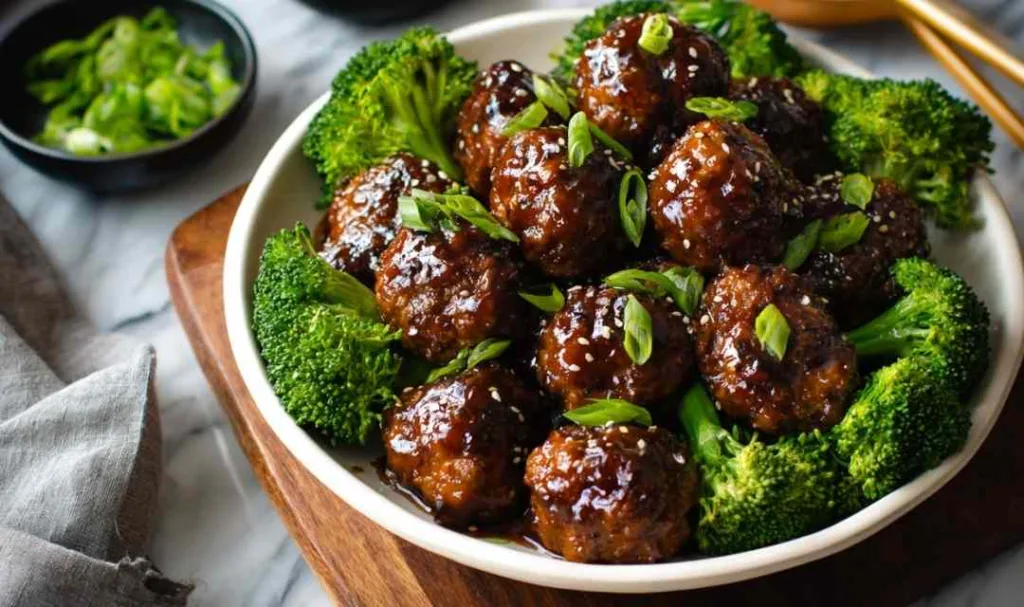 Sticky Mongolian meatballs and broccoli served over white rice with sesame seeds and green onions
