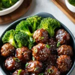Sticky Mongolian meatballs and broccoli served over white rice with sesame seeds and green onions