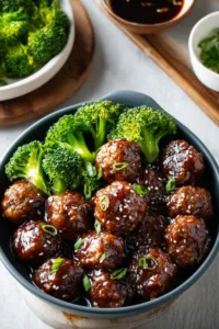 Sticky Mongolian meatballs and broccoli served over white rice with sesame seeds and green onions