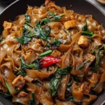 Style Thai Drunken Noodles in white bowl with colorful vegetables and chopsticks