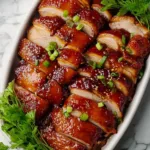 Char siu chicken with glossy caramelized glaze and sesame seeds on white plate