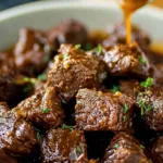 Plated crockpot steak bites over mashed potatoes with parsley garnish