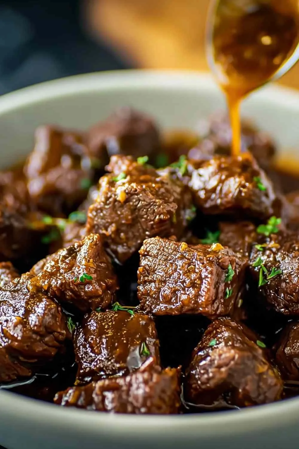 Plated crockpot steak bites over mashed potatoes with parsley garnish
