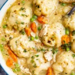 Bowl of easy chicken and dumplings with spoon and fresh thyme garnish