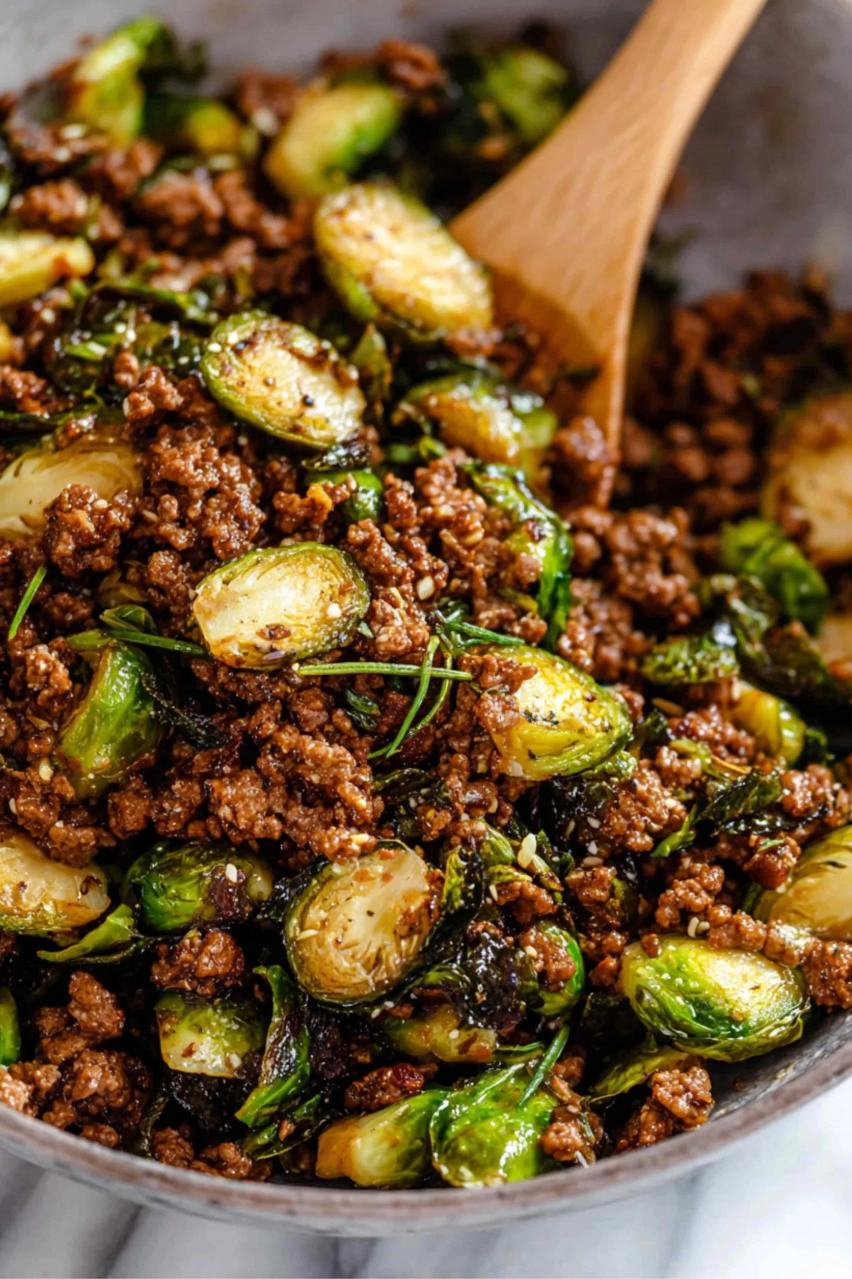 Ground beef and brussels sprouts served over white rice in bowl