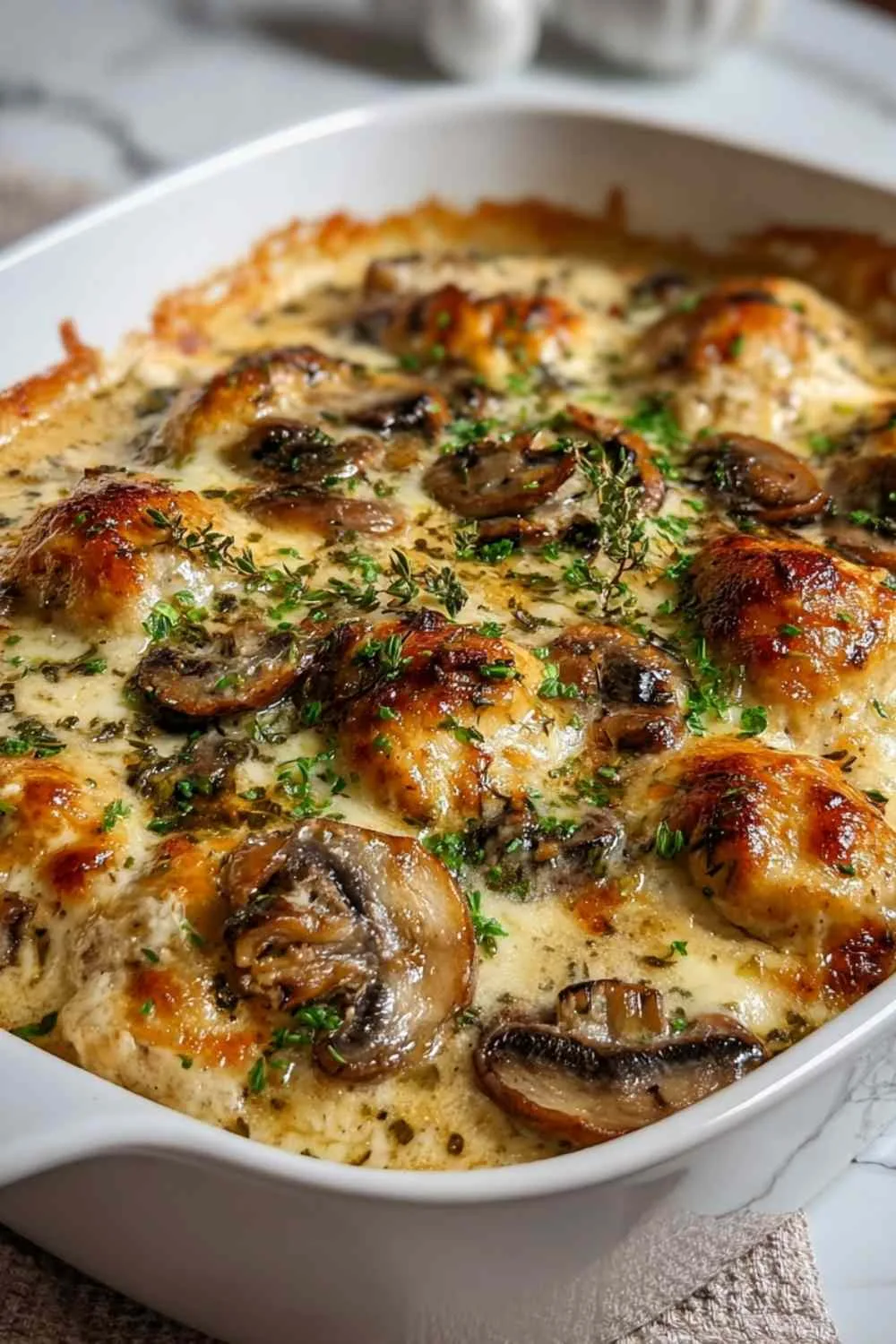 Keto Garlic Mushroom Chicken Casserole bubbling in white dish with golden cheese top