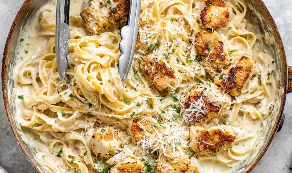 Chicken fettuccine Alfredo with creamy parmesan sauce and golden sliced chicken in a skillet
