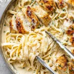 Chicken fettuccine Alfredo with creamy parmesan sauce and golden sliced chicken in a skillet
