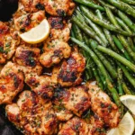 Lemon garlic butter chicken and green beans in a cast iron skillet with parsley and lemon garnish