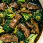Slow cooker beef and broccoli served over white rice with sesame seeds and green onions