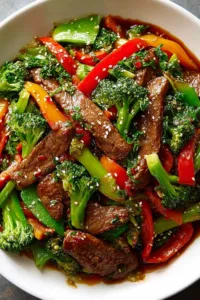 Beef stir fry with fresh vegetables served over steamed jasmine rice in a white bowl