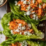 Buffalo Chicken Lettuce Wraps arranged on a platter with blue cheese crumbles and fresh celery.