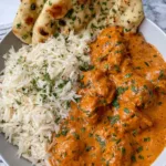 Creamy Butter Chicken Recipe served in a white bowl with basmati rice and naan bread.