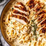 Creamy chicken Alfredo with fettuccine and fresh parsley on a white plate