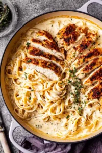 Creamy chicken Alfredo with fettuccine and fresh parsley on a white plate