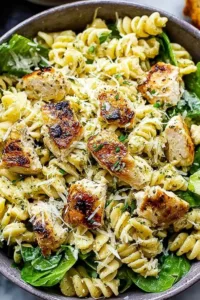 Chicken Caesar pasta salad in a large wooden bowl with romaine, croutons, cherry tomatoes, and Parmesan