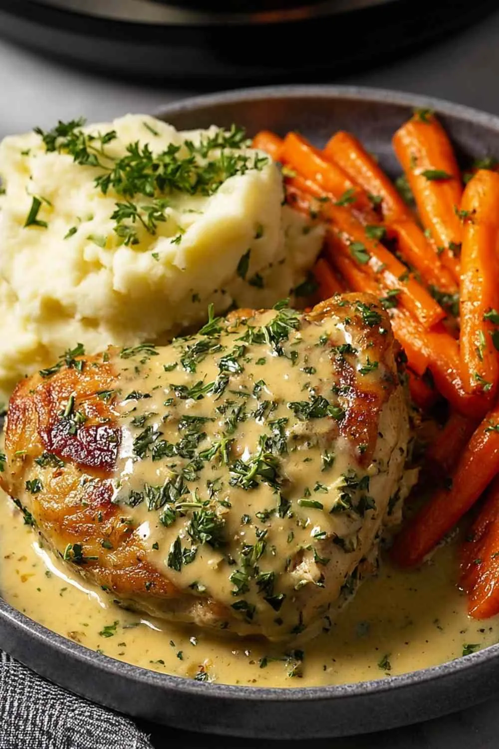 Creamy Herb Chicken with mashed potatoes and glazed carrots on a white plate