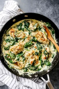 Creamy spinach chicken in a skillet with golden crispy cutlets and garlic cream sauce