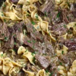 Crock pot beef and noodles in a bowl garnished with fresh parsley
