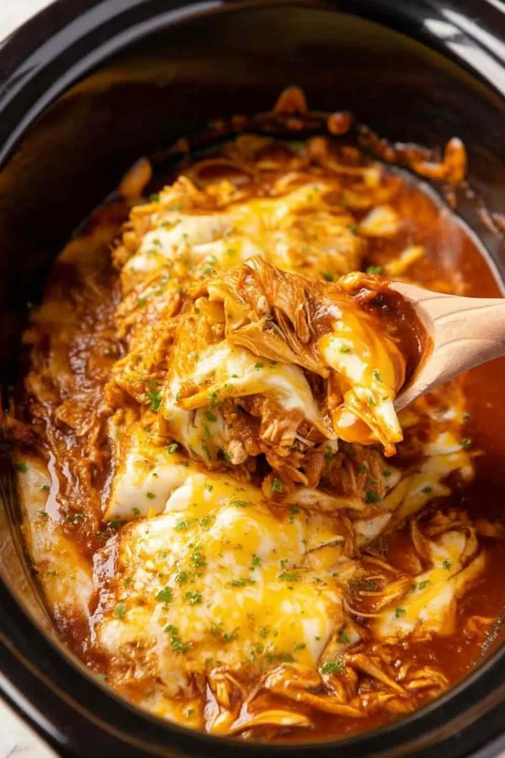 Crockpot chicken enchiladas in slow cooker topped with melted colby jack cheese