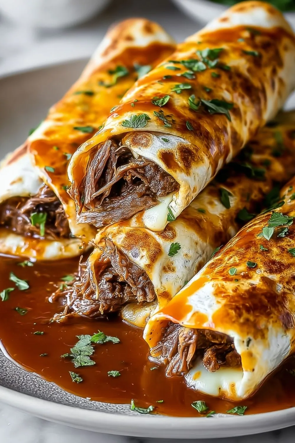 French Dip Tortilla Roll Ups on a wooden board with dipping sauce