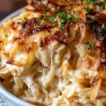 French onion chicken orzo casserole bubbling in a skillet with golden melted cheese