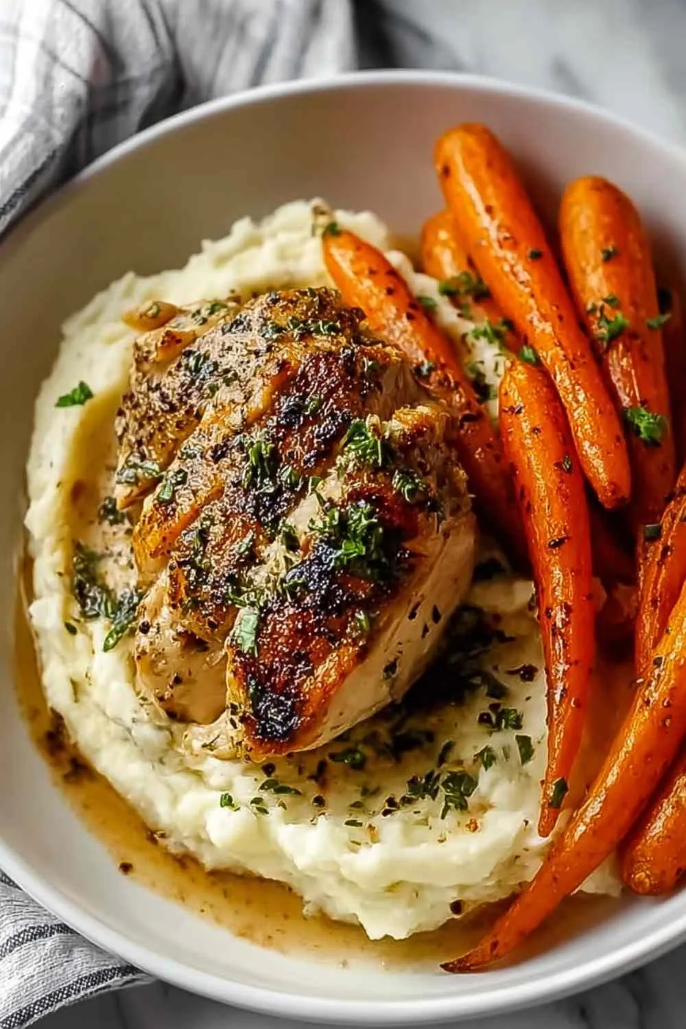 Plate of Garlic Herb Chicken with Creamy Mash & Roasted Carrots garnished with parsley.