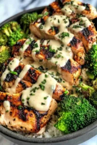 Grilled Chicken and Broccoli Bowls with Creamy Garlic Sauce on a wooden table
