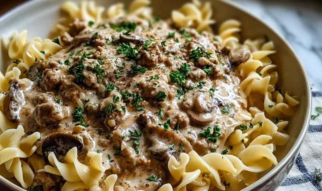 A creamy skillet of Ground Turkey Stroganoff with egg noodles and parsley in a cast iron pan.