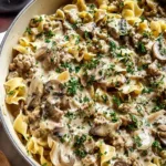 A creamy skillet of Ground Turkey Stroganoff with egg noodles and parsley in a cast iron pan.