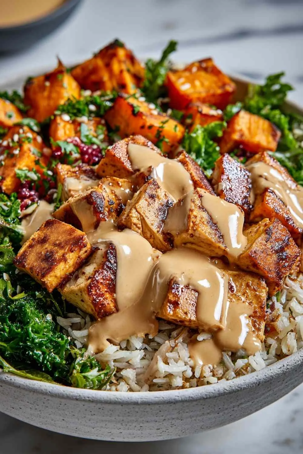 Healthy chicken sweet potato bowls topped with creamy spiced sauce and fresh cilantro