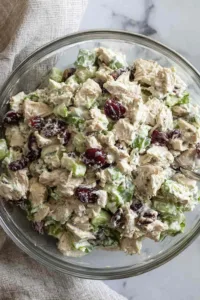 Healthy chicken salad with Greek yogurt dressing being mixed in a large bowl with fresh dill, celery, and red onion