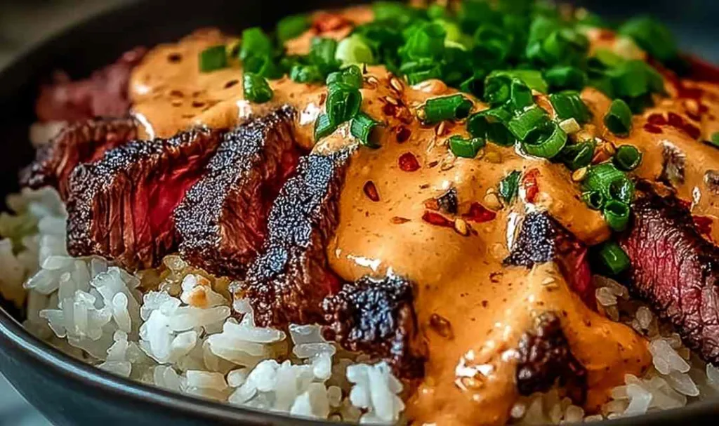 Korean BBQ steak rice bowls with spicy cream sauce on a white table