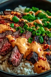 Korean BBQ steak rice bowls with spicy cream sauce on a white table